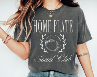 May include: A gray t-shirt with a white graphic of a baseball with a wreath around it and the text "Home Plate Social Club".