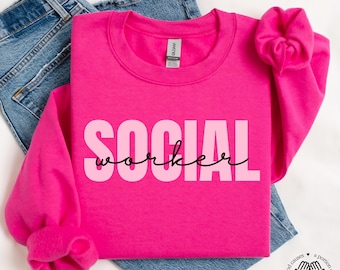 Puede incluir: Sudadera rosa con el texto "SOCIAL worker" en letras negras y rosas.