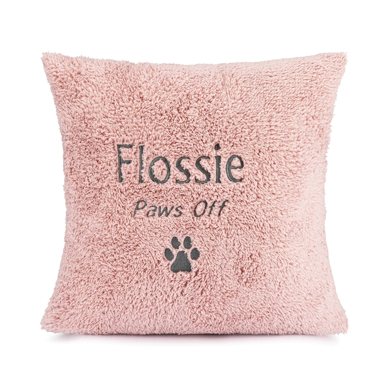 May include: Pink plush pillow with the text "Flossie paws off" and a paw print embroidered on it.