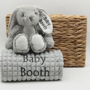 May include: A grey plush bunny with white accents and a grey and white blanket. Both items are embroidered with the text "Baby Booth".