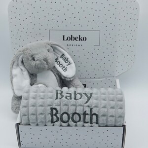 May include: A grey and white plush bunny toy and a grey blanket with the name "Baby Booth" embroidered on it. The items are in a white box with a grey polka dot pattern and the text "Lobeko Designs".