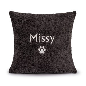 May include: A dark gray plush pillow with the name "Missy" embroidered in white and a white paw print.