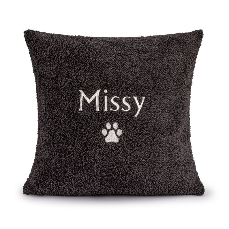 May include: A dark gray plush pillow with the name "Missy" embroidered in white and a white paw print.