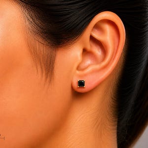 Pu&ograve; includere: Un orecchino a lobo con una pietra nera dal taglio quadrato montata su una montatura in metallo dorato. L'orecchino &egrave; posizionato sul lobo dell'orecchio e una scala indica una dimensione di 5mm per la pietra quadrata come riferimento visivo.