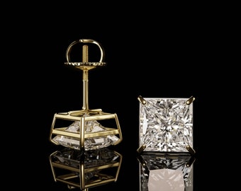 May include: A pair of gold earrings with a square-shaped diamond in a prong setting. The earrings are on a black background.