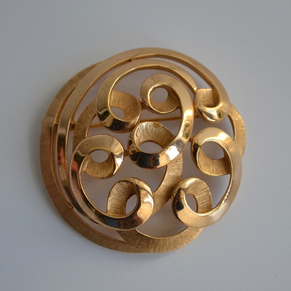 1950s Crown Trifari USA. Goldtone Trifarium Continuous ribbon swirl Circular, dome vintage pin brooch.