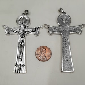 May include: Two silver metal crucifixes. The crucifix on the left features a depiction of Jesus Christ on the cross. The crucifix on the right has the words "Tertium Millennium" inscribed on the crossbar.