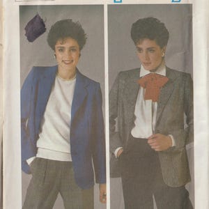 May include: Simplicity sewing pattern featuring two women modeling blazers and trousers. The pattern number is 6724. One woman wears a blue blazer, white sweater, and plaid pants. The other wears a gray blazer, white shirt, and dark pants.