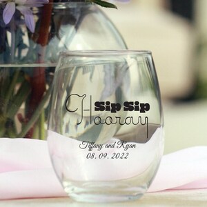May include: Clear glass stemless wine glass with a black graphic that says "Sip Sip Hooray" and the text "Tiffany and Ryan 08.09.2022".