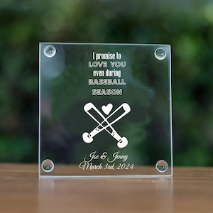 May include: A clear glass coaster with a white design of two crossed baseball bats and a heart. The text "I promise to LOVE YOU even during BASEBALL SEASON" is printed on the coaster. The names "Joe & Jenny" and the date "March 3rd, 2024" are also printed on the coaster.