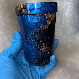 May include: A blue and gold tumbler with a metallic finish. The tumbler has a lid and a gold glitter design.