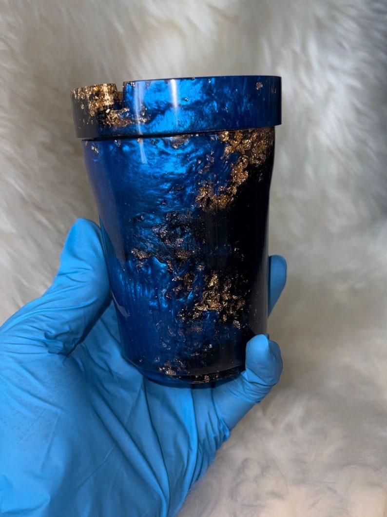 May include: A blue and gold tumbler with a metallic finish. The tumbler has a lid and a gold glitter design.