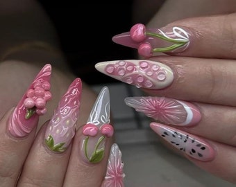 May include: A set of long, sculpted acrylic nails with a variety of pink fruit-themed designs. The nails feature 3D cherries, strawberries, and a slice of a dragon fruit. Other nails have bubble and floral designs.