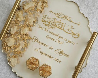 May include: A white and gold decorative tray with gold handles. The tray features gold leaf accents and gold text that reads "And We created you in pairs" and names "Shayaan & Aleena" with a date. Two hexagonal coasters are also included.