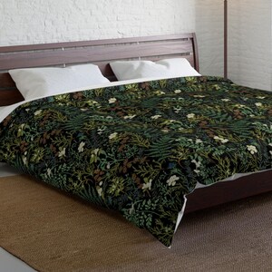May include: A dark green and white floral duvet cover with a botanical print. The duvet cover is on a bed with a wooden headboard and a brown rug.