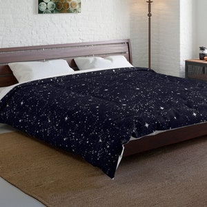 May include: A dark blue duvet cover with a white star pattern. The duvet cover is on a bed with white pillows and a brown wooden frame.