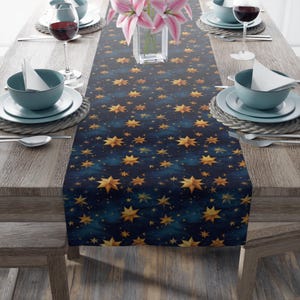 May include: A navy blue table runner with a gold star pattern. The runner is decorated with a repeating pattern of gold stars on a dark blue background. The stars are of varying sizes and have a slightly distressed look.