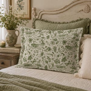 May include: A rectangular pillow sham featuring a repeating pattern of green rabbits, butterflies, and various botanical elements like ferns and flowers printed on a white background, finished with a simple hemmed edge.
