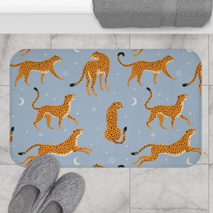 May include: A blue bath mat with a repeating pattern of orange cheetahs and white stars on a light blue background.