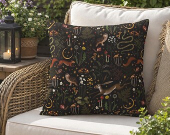 May include: A square throw pillow featuring a dark black background with a repeating pattern of woodland elements including brown owls, a running hare, a squirrel, a snake, various mushrooms, ferns, small white flowers, and golden crescent moons.