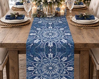 May include: A rectangular table runner featuring a deep blue fabric base with a repeating white snowflake and star pattern. The runner is centered on a wooden dining table, showcasing intricate geometric winter-themed designs in white.