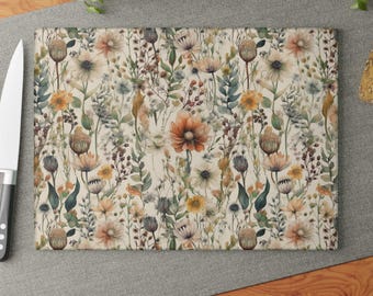 May include: A white cutting board with a floral pattern featuring various shades of brown, yellow, and green. The flowers are watercolor-style and create a delicate and whimsical design.