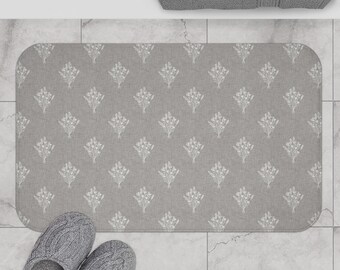 May include: A gray bath mat with a white floral pattern. The mat is made of a soft, absorbent material and is perfect for adding a touch of style to your bathroom.