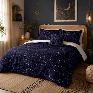 May include: A navy blue bedding set featuring a white star pattern, including a comforter, two rectangular pillows, and one square accent pillow. The bedding is displayed on a bed with a light brown woven headboard and white sheets.