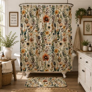 May include: A shower curtain and matching bath mat featuring a watercolor-style botanical print with orange, yellow, and muted green wildflowers, stems, and seed pods on a cream-colored background, suspended from a metal rod with rings.