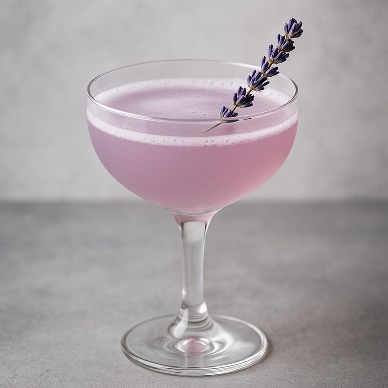 K&ouml;nnte beinhalten: Ein Lavendel-Cocktail in einem Coup&eacute;-Glas mit einem Lavendelzweig als Garnitur.