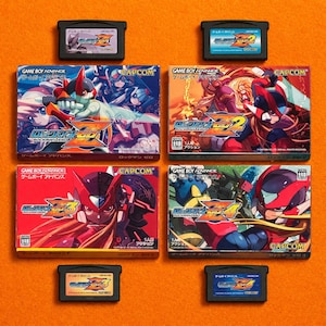 Puede incluir: Una colección de cartuchos y cajas de videojuegos de Game Boy Advance. Las cajas presentan ilustraciones coloridas de personajes de la serie "Rockman Zero", con texto japonés y el logotipo de Capcom. Los cartuchos son negros.