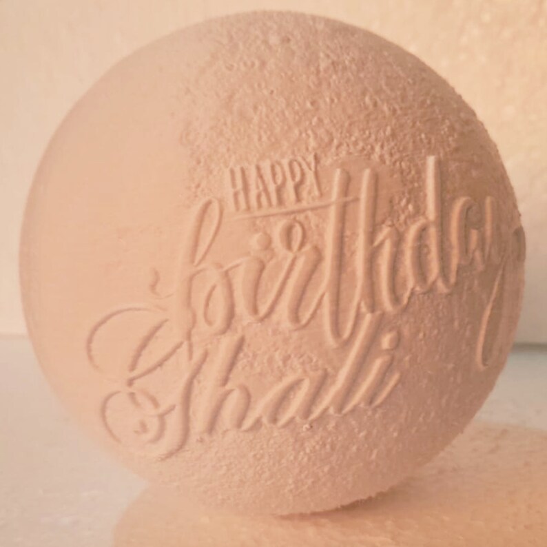 May include: White ceramic sphere with the words "Happy Birthday Shalli" embossed on the surface.