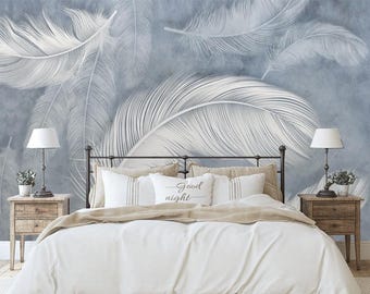 May include: A white bed with a black metal frame and white bedding. The headboard is against a wall with a blue and white feather pattern. Two bedside tables with lamps are on either side of the bed. The pillows have the text "Good night" on them.