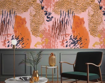 May include: A living room interior design featuring a pink and orange abstract patterned wallpaper, a green velvet armchair, a gold pineapple decorative object, a gold metal side table, a white marble coffee table, and a potted plant.