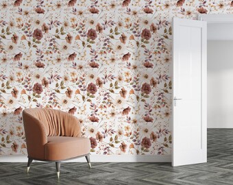 Puede incluir: Una habitación con papel pintado floral y un sillón melocotón. El papel pintado tiene un fondo blanco con flores de acuarela en tonos marrón, melocotón y morado. El sillón tiene patas oscuras con puntas doradas.