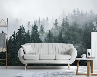 May include: A white sofa with a tufted back and a foggy forest scene wallpaper behind it. The sofa is in a living room setting with a wooden coffee table and a clock on a white shelf.