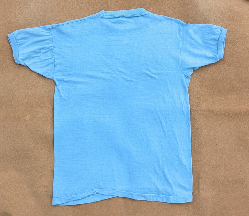 K&ouml;nnte beinhalten: Ein hellblaues T-Shirt mit geripptem Rundhalsausschnitt und kurzen &Auml;rmeln.