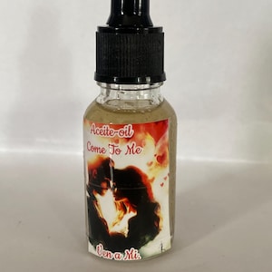May include: A clear glass bottle with a black dropper top. The bottle has a label with the words "Aceite-oil Come To Me" and "Ven a Mi" over an image of a couple. The liquid inside the bottle is a light brown color.
