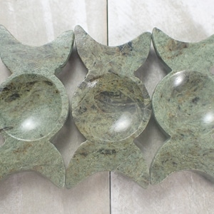 May include: Three green stone bowls with a crescent moon design. The bowls are made of a natural stone with a marbled pattern.