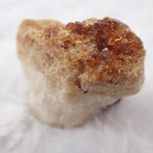 May include: A cluster of small, translucent, amber-colored crystals on a white, opaque base.