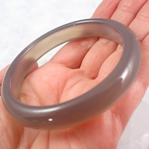 May include: A gray agate bangle bracelet. The bracelet is smooth and polished, with a subtle sheen.