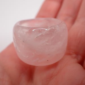 Peut inclure: Une bague en quartz rose lisse, de couleur rose pâle, de forme arrondie et légèrement irrégulière.