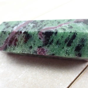 May include: A green, black, and pink zoisite crystal point with a rough, natural finish.
