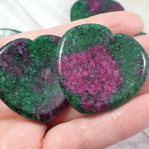 May include: Two green and pink heart-shaped stones with a rough, textured surface.