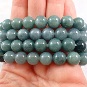 May include: A stack of four jade bracelets with round, light blue beads. The bracelets are stacked on top of each other, with the top bracelet being the smallest and the bottom bracelet being the largest.