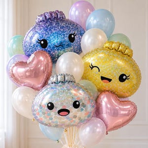 May include: A balloon bouquet featuring three large, round, character-shaped foil balloons in blue, yellow, and iridescent silver, each with a printed face. Two metallic pink heart-shaped balloons and several smaller round latex balloons in white, light blue, lavender, and mint green are interspersed throughout the arrangement.