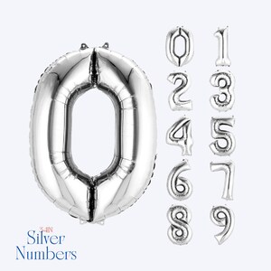 May include: A large silver foil balloon in the shape of the number zero, accompanied by a vertical column of smaller silver foil balloons representing the numbers zero through nine. The text 34IN Silver Numbers is visible at the bottom left.