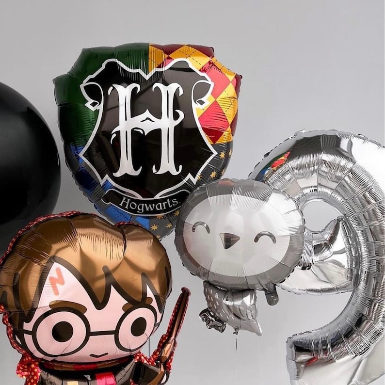 May include: A set of Harry Potter themed balloons, including a silver number 9 balloon, a silver balloon shaped like an owl, a brown balloon with a cartoon image of Harry Potter, and a black and gold balloon with the Hogwarts crest and the letter "H" in white.