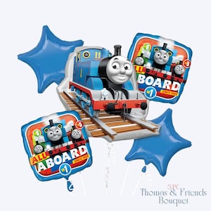 May include: A Thomas the Tank Engine balloon bouquet. The centerpiece is a blue and white train balloon with a smiling face, surrounded by blue star-shaped balloons and square balloons with the text "All Aboard" and "Since 1945".