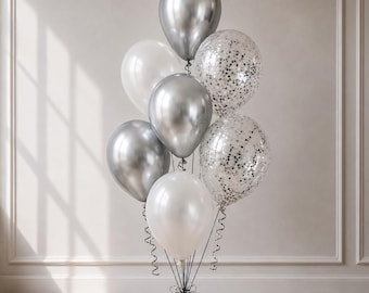 May include: A balloon bouquet featuring a mix of solid metallic silver balloons, opaque white balloons, and clear balloons filled with silver confetti. The balloons are tied together with silver ribbons at the base, creating a festive arrangement.